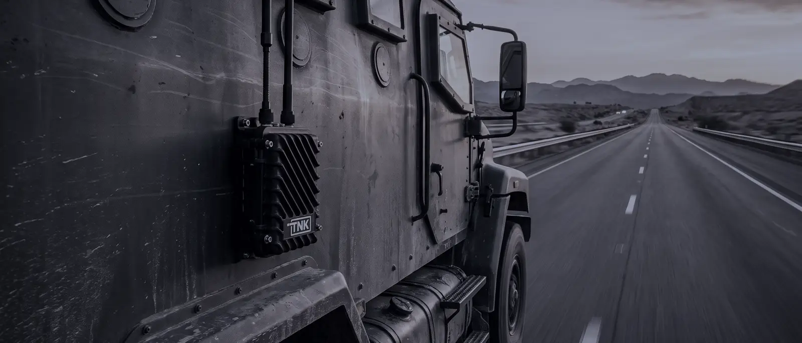Equipo de Tank montado en el costado de un camión blindado que avanza por una carretera al atardecer